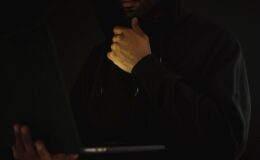 crop pensive hacker using laptop and touching chin